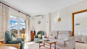 A living room with a sofa, chairs, a wooden coffee table, and a balcony with a view.