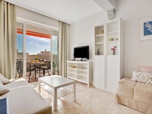 A modern living room with a TV, a dining area, and a sofa.