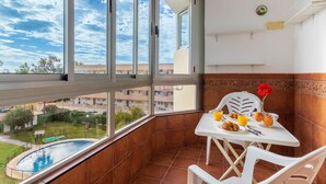 A balcony with a pool view, a table with breakfast items, and a chair. - Vistamarina 405B - Terrace, Swimming Pool, 300m from beach (Torremolinos)