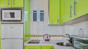 A kitchen with green cabinets, a white refrigerator, a microwave, a kettle, and a coffee machine. - Vistamarina 405B - Terrace, Swimming Pool, 300m from beach (Torremolinos)