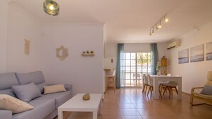 A modern living room with a sofa, coffee table, and dining area. - Imperial Puerto 3E - Terrace, Swimming Pool, 200m from the beach (Torremolinos)