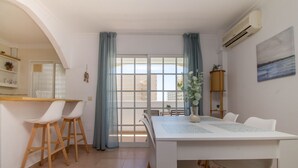 A modern kitchen with a white countertop, wooden stools, and a dining table with chairs. - Imperial Puerto 3E - Terrace, Swimming Pool, 200m from the beach (Torremolinos)