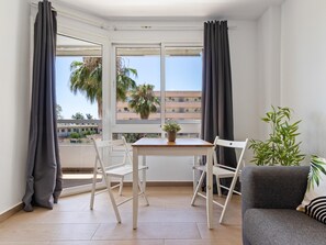 A small room with a table and chairs, a sofa, and a window with curtains. - Vistamarina 211B - Terrace, Pool, Garage. 300m from the beach (Torremolinos)