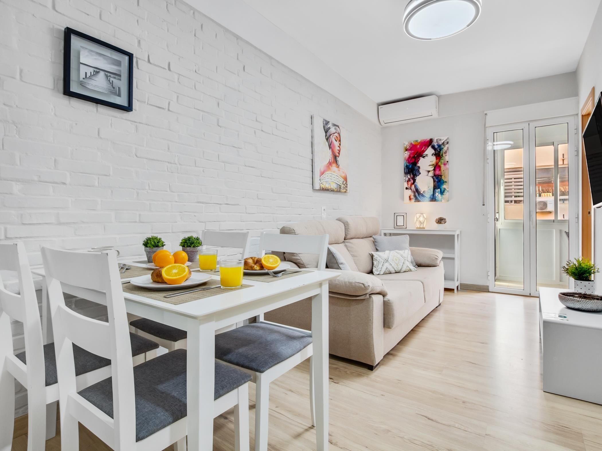 Um espaço de estar moderno com área de jantar, um sofá e uma pequena mesa com uma planta.