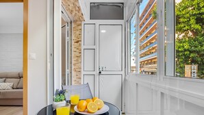 A modern room with a glass table set with a plate of oranges and a glass of orange juice, a sofa, and a door with a view of a building with balconies. - Los Nidos - 1 bedroom, Terrace, 100 m from the beach (Torremolinos)