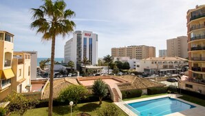 Un hôtel doté d’une piscine sur le toit, de palmiers et offrant une vue sur la mer.