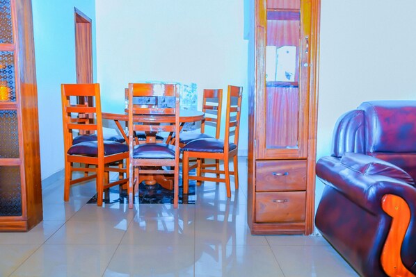 A dining area with a wooden table and chairs, a sofa, and a cabinet.