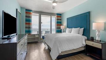 Relax in a spacious room with a large bed, flanked by a dresser and nightstand, and enjoy a view of the sky from the large window.