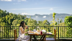 Una mesa de comedor con comida y bebidas, con vistas a un paisaje montañoso.