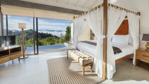 Un dormitorio amplio con una cama grande, una banca, un televisor y vistas a las montañas.
