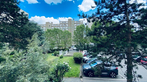 Un balcón con vistas a un jardín cuidado y zonas verdes en una zona residencial.