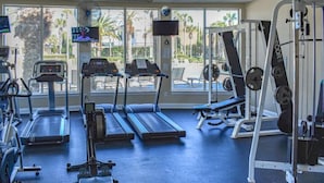 Un gimnasio con cintas de correr, máquinas de pesas y una pantalla de televisión.
