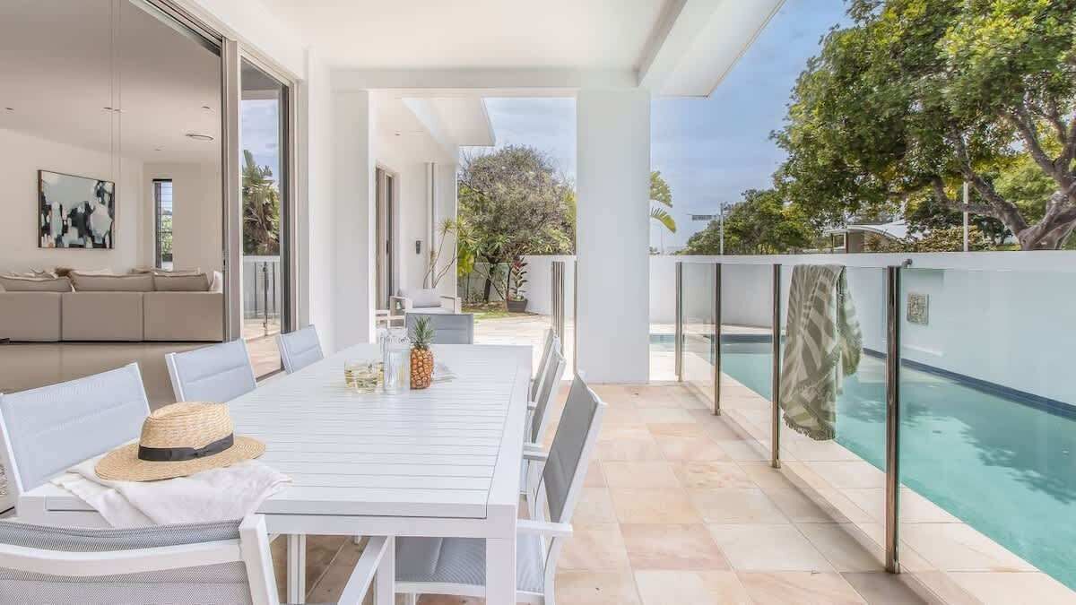 An outdoor dining area with a table and chairs, a pool, and a view of the surrounding landscape.