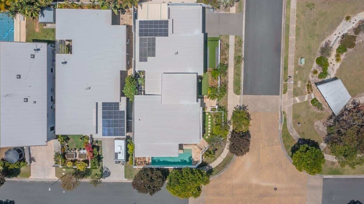 A multi-story building with a flat roof, solar panels, and a swimming pool.