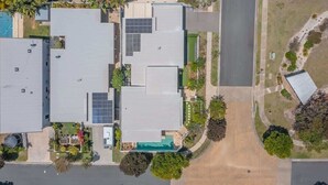 Un edificio de varios pisos con techo plano, paneles solares y una piscina.