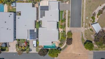 A multi-story building with a flat roof, solar panels, and a swimming pool.