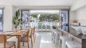 A modern kitchen with a dining area, large windows, and a view of the outside.