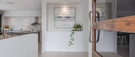 Una cocina moderna con una isla central, una planta colgante y un ventanal grande.