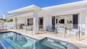 Una casa moderna con piscina, zona de estar exterior y patio cubierto.