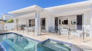 A modern house with a swimming pool, outdoor seating, and a covered patio area. - Elliston House (Kingscliff)