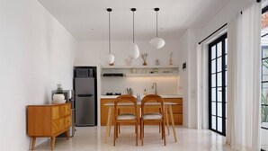 A modern kitchen with a dining area, a sofa with cushions, and a large window with curtains. - Splendid Villa Eden White Canggu Pool & 2 Bd (Canggu)