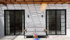 A modern room with a sofa, a colorful abstract sculpture, and large windows casting shadows on the floor. - Splendid Villa Eden White Canggu Pool & 2 Bd (Canggu)