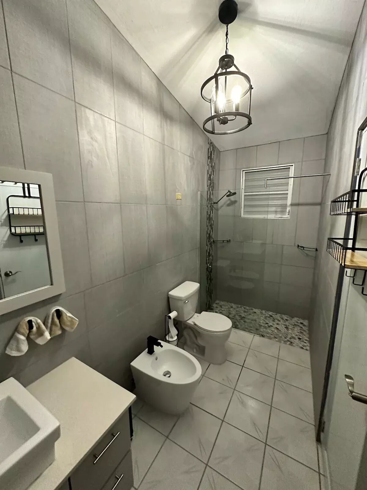 Une salle de bain moderne comprenant des toilettes, un bidet, un lavabo et un espace douche.