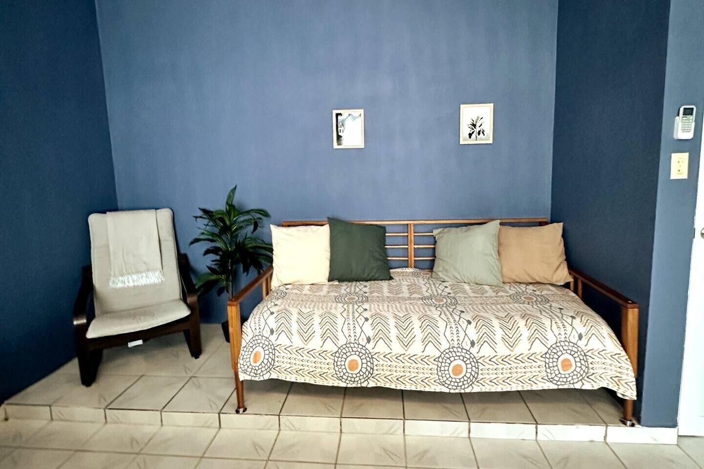 A bedroom with a bed, a chair, and a potted plant.