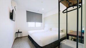 A hotel room with a bed, a small table with a lamp, a window with a blind, and a mirror with a wooden frame. - The Concept Hotel Melaka City (Malacca City)