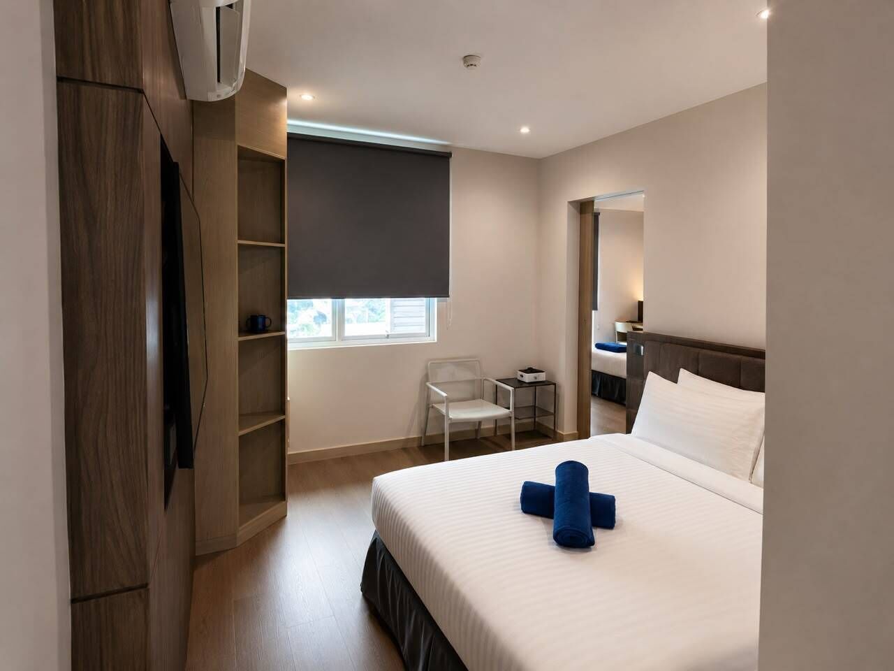 Una habitación de hotel con cama, escritorio, silla, armario y ventana.