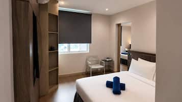 Ein Hotelzimmer mit Bett, Schreibtisch, Stuhl, Kleiderschrank und Fenster.