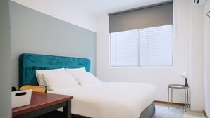 A neatly arranged hotel room with a bed, a small table, a chair, and a window with blinds. - The Concept Hotel Melaka City (Malacca City)
