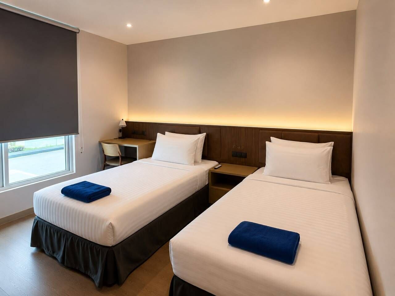 Una camera d'albergo con due letti, una scrivania e una finestra.