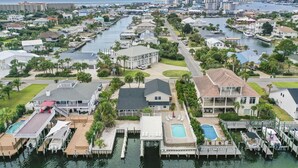 A waterfront property with multiple docks, a swimming pool, and a large house with a spacious deck. - 5BR Waterfront Retreat with Pool, Boat Slips + Dock | Boater’s Dream House (Destin)
