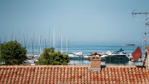 Eine Marina mit mehreren angestuften Segelbooten, einem strahlend blauen Himmel und einer in der Ferne liegenden Insel.