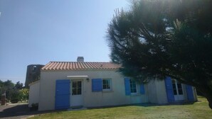 Una casa de un piso con techo de tejas, contraventanas azules y un pequeño porche.