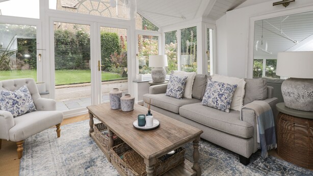 A spacious room with a large window, a sofa, a coffee table, and a lamp. - The Gate House (Cirencester)