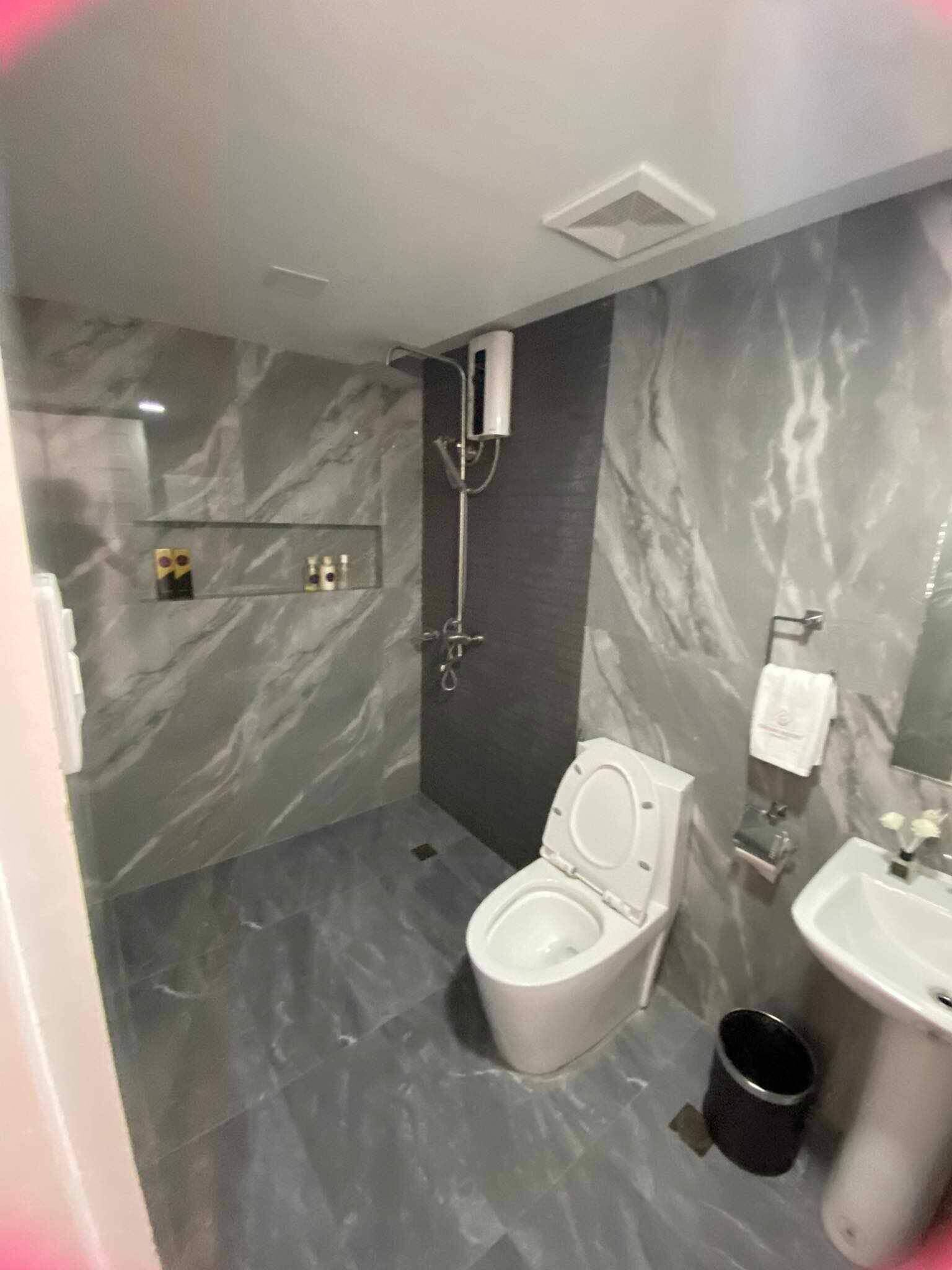 Un baño moderno con suelo de mármol, inodoro, lavabo y ducha.