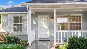 Une maison de plain-pied avec un porche à l’avant, une porte et un petit jardin.