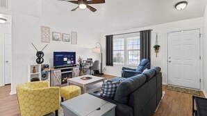 Un salon avec un canapé, des fauteuils, un téléviseur et une cheminée.