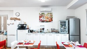 Uma cozinha moderna com armários brancos, uma geladeira, uma cafeteira e um balcão para refeições.