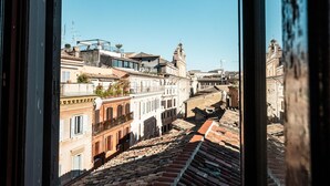 Vista pela janela de um horizonte urbano com edifícios históricos e telhado em telhas.