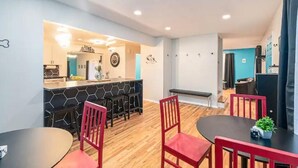 Un espace repas moderne aux couleurs noir et rouge, avec une table ronde centrale et des chaises rouges.