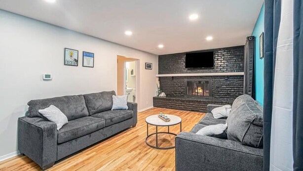 Un salon moderne avec une cheminée, deux canapés, une table basse et un téléviseur fixé au mur.
