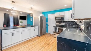 Une cuisine moderne avec des meubles blancs, un plan de travail en marbre noir et un mur d’accent bleu.