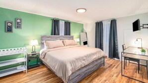 Une chambre à coucher comprenant un lit, des tables de chevet, un banc, un bureau et une chaise.