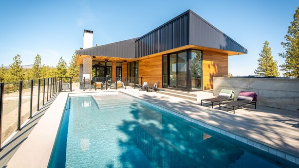 Ein modernes Haus mit Schwimmbad, großen Fenstern und Sitzgelegenheiten im Freien.