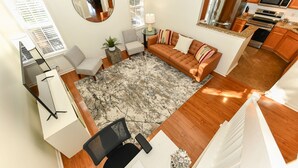 A spacious living area with a sofa, a coffee table, and a rug. There is a kitchen with modern appliances and wooden cabinets.