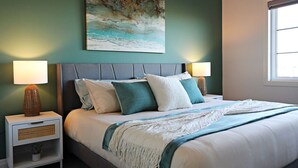 Ein Schlafzimmer mit einem Bett, zwei Nachttischen, einem Wandbild und einem Fenster.