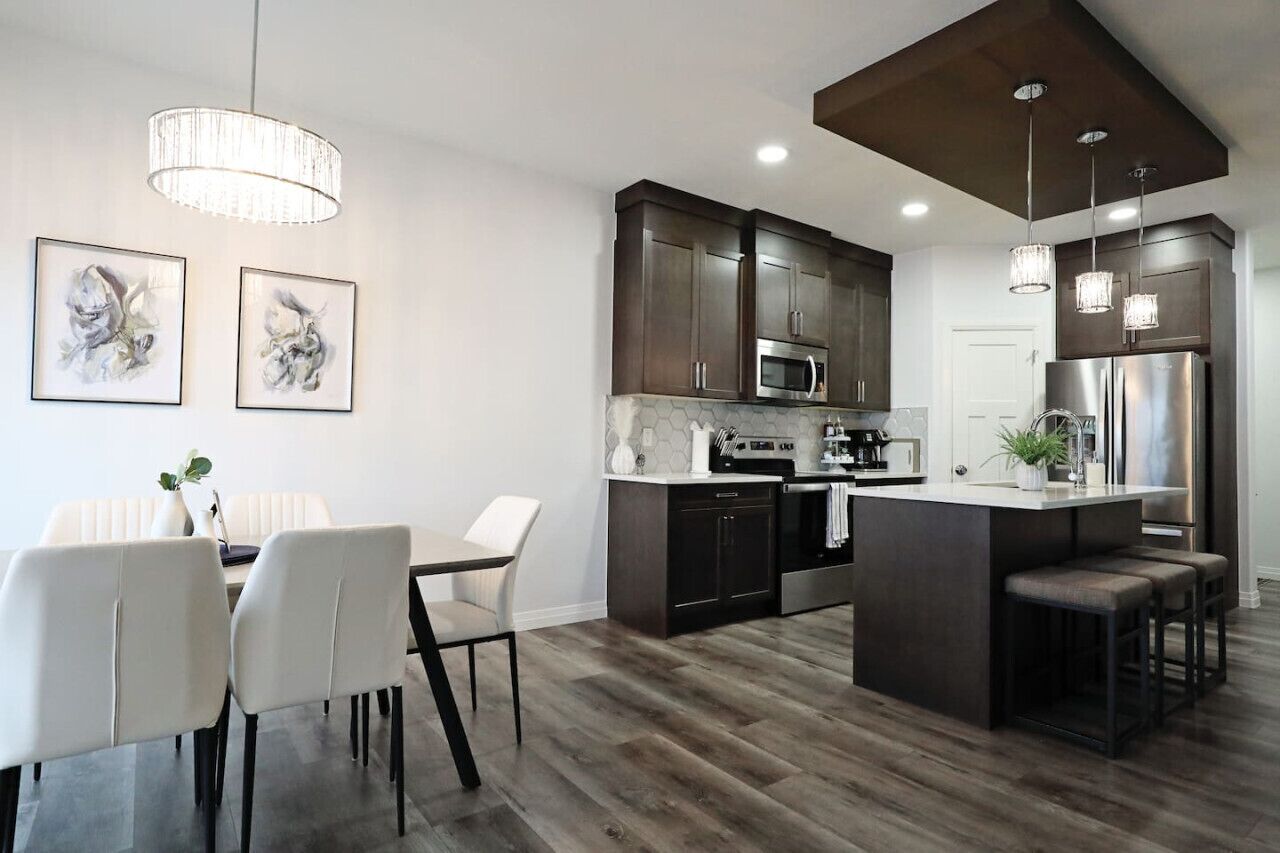 A modern kitchen with dark cabinets, a central island, and pendant lighting.